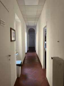 A hallway with white walls and a red tile floor.